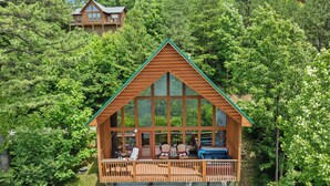 Una cabana de fusta amb un balcó gran, envoltada per un bosc dens.