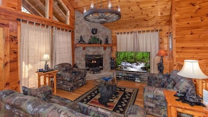 A cozy log cabin interior with a fireplace, plush sofas, and a stone accent wall. - Easy Access Roads*In Pigeon Forge*Jacuzzi and hot tub (PIGEON FORGE)