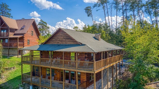 A multi-story log cabin with a balcony on the upper floor, surrounded by trees and a clear sky. - Easy Access Roads*In Pigeon Forge*Jacuzzi and hot tub (PIGEON FORGE)