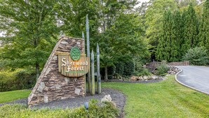 A sign for Sherwood Forest with a stone and wooden structure, surrounded by greenery and a curved road.