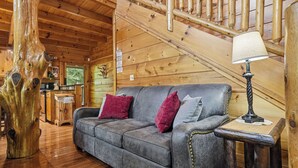 A wooden interior with a grey sofa, a wooden staircase, and a table with a lamp. - Resort*Luxury*Close to Pigeon Forge*Game Loft*Seasonal Pool (SEVIERVILLE)