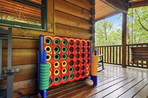 A wooden cabin with a wooden deck, a colorful board game, and a bench.