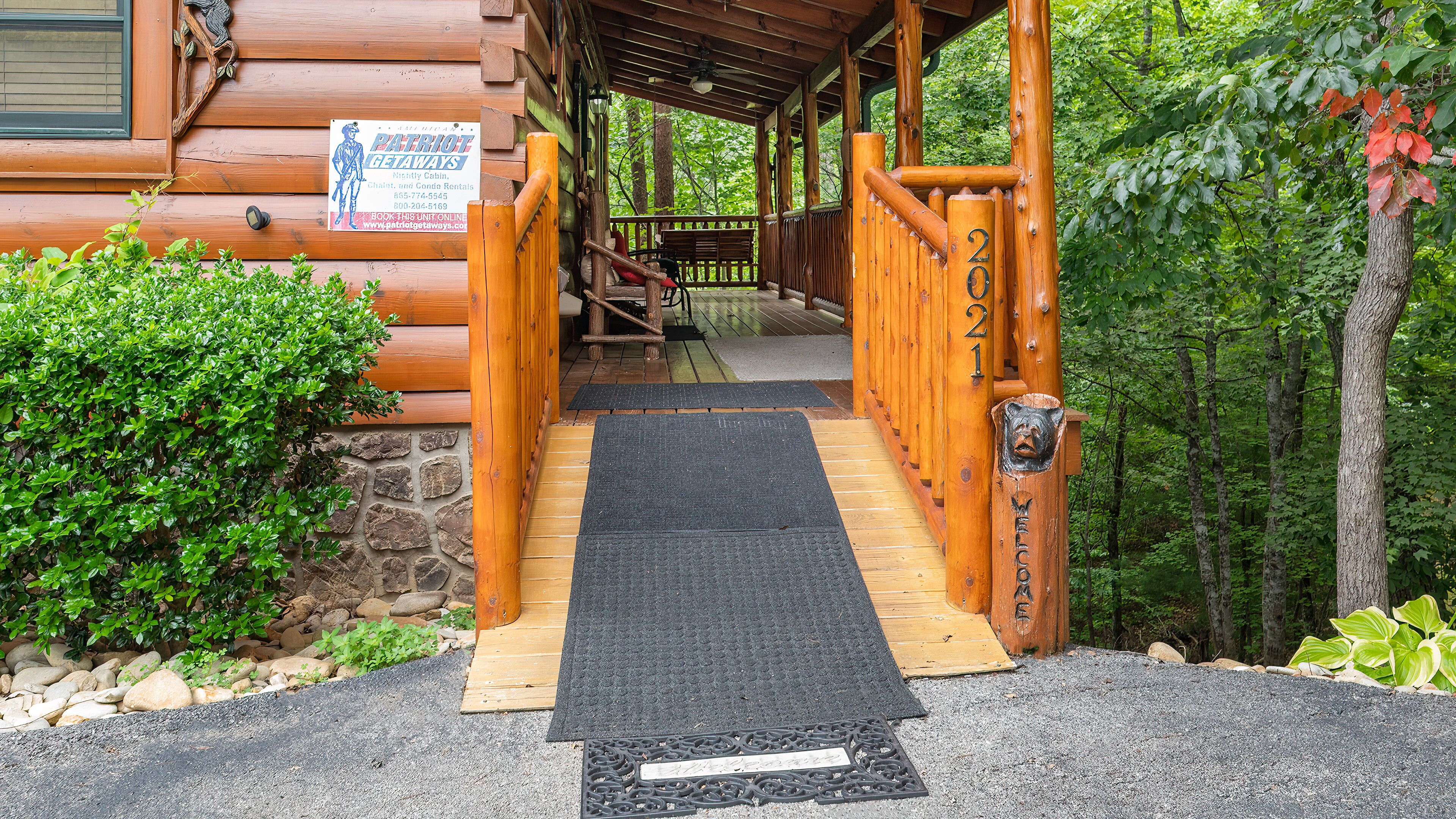 L’entrée d’un chalet en bois, avec un porche, une pancarte de bienvenue et le chiffre « 2021 » inscrit sur un poteau.