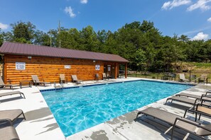 Una cabaña de madera con piscina, sillas de descanso y un letrero que indica agua poco profunda y prohibido bucear.