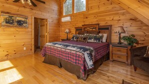 A wooden cabin bedroom with a bed, nightstands, a ceiling fan, and a large window. - Pigeon Forge*Mountain Views*Family Fun*Game Room*Hot Tub (PIGEON FORGE)