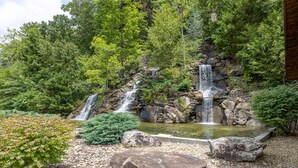 A waterfall surrounded by lush greenery and a small pond. - Pigeon Forge*Mountain Views*Family Fun*Game Room*Hot Tub (PIGEON FORGE)