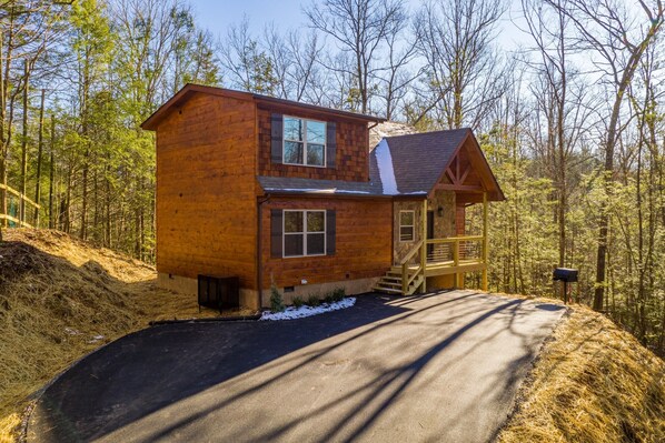 Une cabane en bois à deux étages, dotée d’un porche couvert et d’un escalier menant à l’étage supérieur.