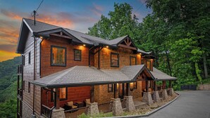 A log cabin with a stone porch, multiple windows, and a view of the surrounding forest. - Wears Valley*Mtn Views*Tons of Great Amenities*Gated Resort (PIGEON FORGE)