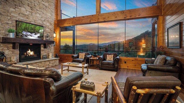 A cozy living room with leather furniture, a fireplace, and large windows offering a scenic view. - Wears Valley*Mtn Views*Tons of Great Amenities*Gated Resort (PIGEON FORGE)