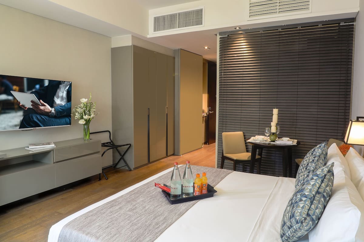 Une chambre d’hôtel moderne équipée d’un lit, d’une télévision, d’un bureau et d’un coin repas.