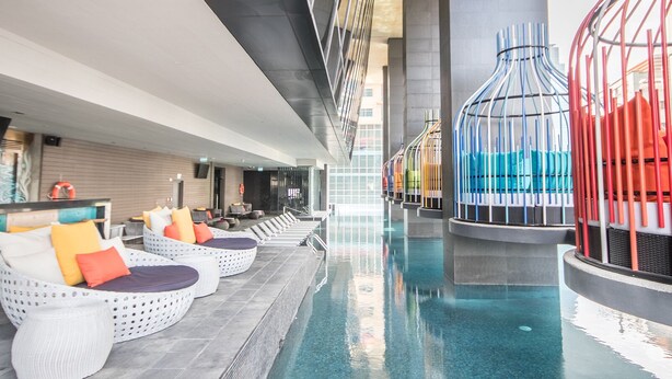 Un espace piscine doté de chaises longues et agrémenté d’une fontaine ou d’un élément décoratif aquatique aux couleurs vives.