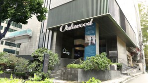Un bâtiment moderne avec une enseigne indiquant « Oakwood Makati Avenue » et un écran numérique.