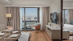 Une chambre d’hôtel moderne avec vue sur la ville, une télévision à écran plat, un coin repas et un lit.