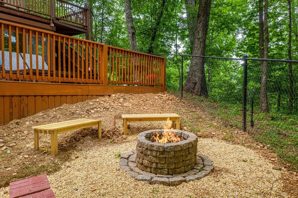 A wooden deck with a fire pit and benches.