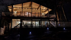 A two-story wooden structure with a balcony, surrounded by trees.