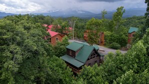 A cabin-style resort surrounded by dense forest, with multiple buildings featuring green roofs and wooden exteriors. - Gatlinburg*Hot Tub*Wifi/Cable*Resort Pool (Seasonal) (GATLINBURG)