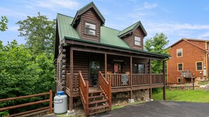 A log cabin with a porch and a staircase leading to the entrance. - Gatlinburg*Hot Tub*Wifi/Cable*Resort Pool (Seasonal) (GATLINBURG)
