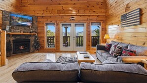 A log cabin interior with a fireplace, television, and a couch.