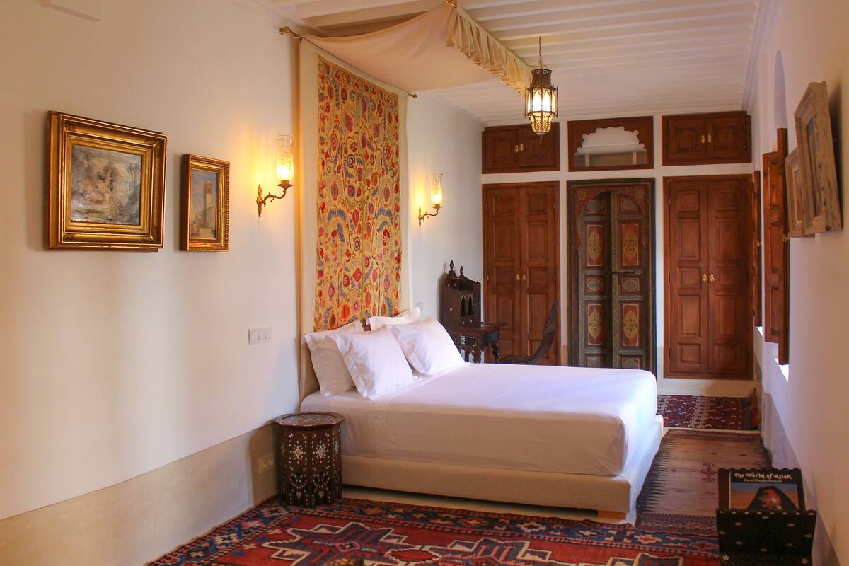 A bedroom with a bed, a patterned curtain, and wooden doors.