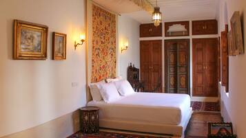 Un dormitorio con cama, cortina estampada y puertas de madera.