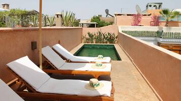 Zona de piscina en la azotea con sillones de descanso y una piscina pequeña.