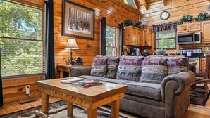 L'intérieur d'un chalet en bois, avec un canapé, une table et un coin cuisine.