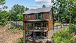 A multi-story wooden cabin with balconies, surrounded by trees and a dirt path. - Gatlinburg*Resort*Breathtaking Views*Keurig*Wifi*Hot Tub (GATLINBURG)