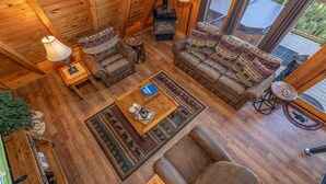 A cozy cabin interior with wooden walls and floors, furnished with leather sofas and armchairs, a coffee table, and a lamp. - Views*Close to Dollywood*Keurig*Pool Table*Wifi*Resort Pool (PIGEON FORGE)