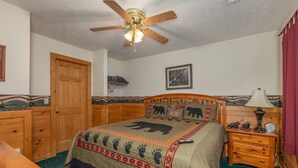 A bedroom with a wooden bed, a ceiling fan, a wooden dresser, and a nightstand with a lamp. - Perfect Family Vacation Cabin (GATLINBURG)