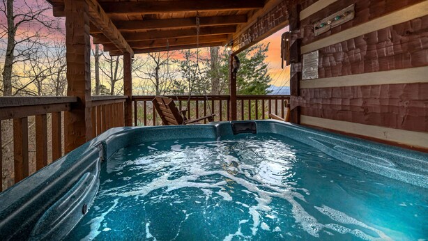 A hot tub under a wooden deck with a view of trees and mountains. - Rustic Studio*Mountain Views*Jacuzzi*Romantic (PIGEON FORGE)