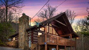 A rustic cabin with a stone chimney, wooden deck, and a satellite dish. - Rustic Studio*Mountain Views*Jacuzzi*Romantic (PIGEON FORGE)