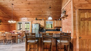 A wooden cabin interior with a dining area, kitchen, and bar seating. - Luxury Log Home*Views*Close to Pigeon Forge*WiFi*Hot Tub (PIGEON FORGE)