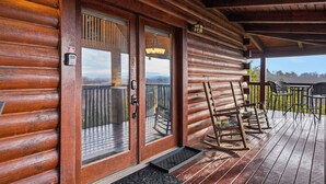 Una cabaña de madera con un porche, mecedoras y vistas a las montañas.