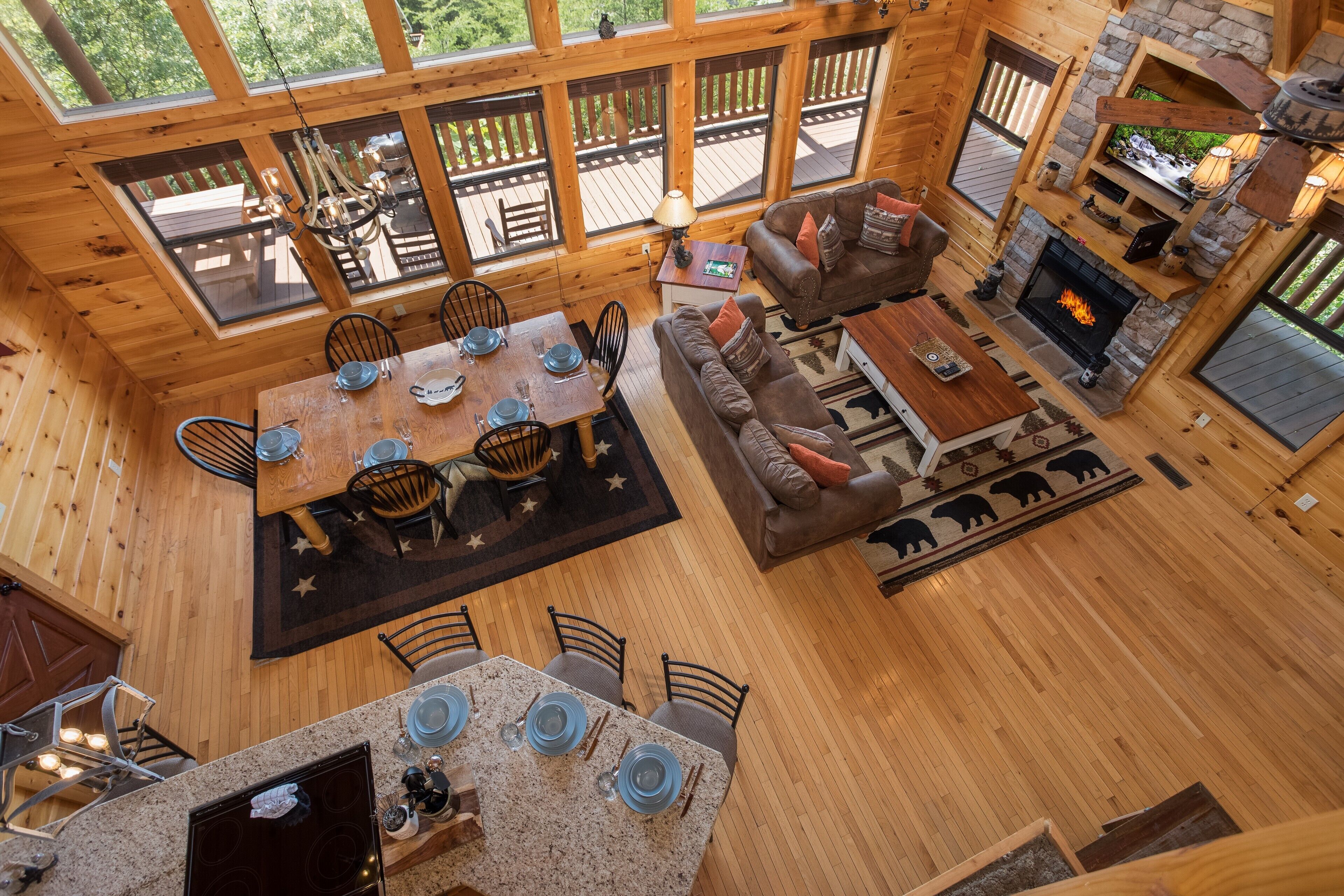 Une cabane en bois spacieuse comprenant un coin repas, un salon et une cheminée.