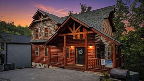 A log cabin with a stone foundation, a porch, and a sign indicating no parking. - Cabin with Indoor Pool and Lots of Entertainment (PIGEON FORGE)