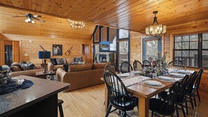 A wooden interior with a dining table set for six, a sofa, a television, and a ceiling fan. - 4-Bedroom Cabin near Dollywood (SEVIERVILLE)