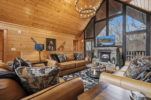 Un intérieur chaleureux de chalet en bois, avec une cheminée, des meubles en cuir et de grandes fenêtres.
