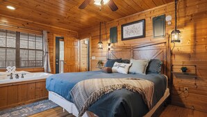 A wooden cabin bedroom with a large bed, a bathtub, and a ceiling fan. - 4-Bedroom Cabin near Dollywood (SEVIERVILLE)