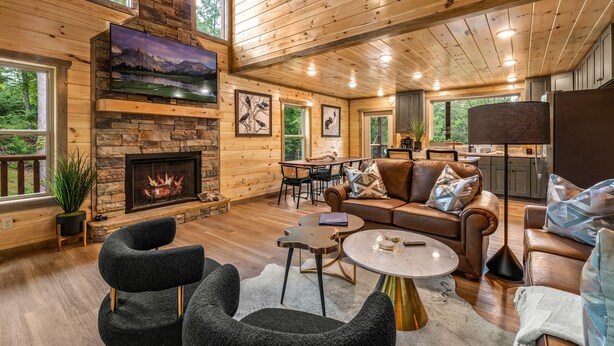 Un salon spacieux doté d’une cheminée, d’un plafond en bois et de grandes fenêtres.