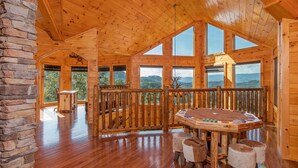 A spacious wooden cabin with a high ceiling, large windows, a wooden deck, and a cozy seating area. - Luxurious 5-Bedroom Cabin with Indoor Pool (SEVIERVILLE)