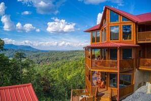 Une cabane en bois à plusieurs niveaux, dotée de balcons, qui se dresse sur fond de paysage montagneux.