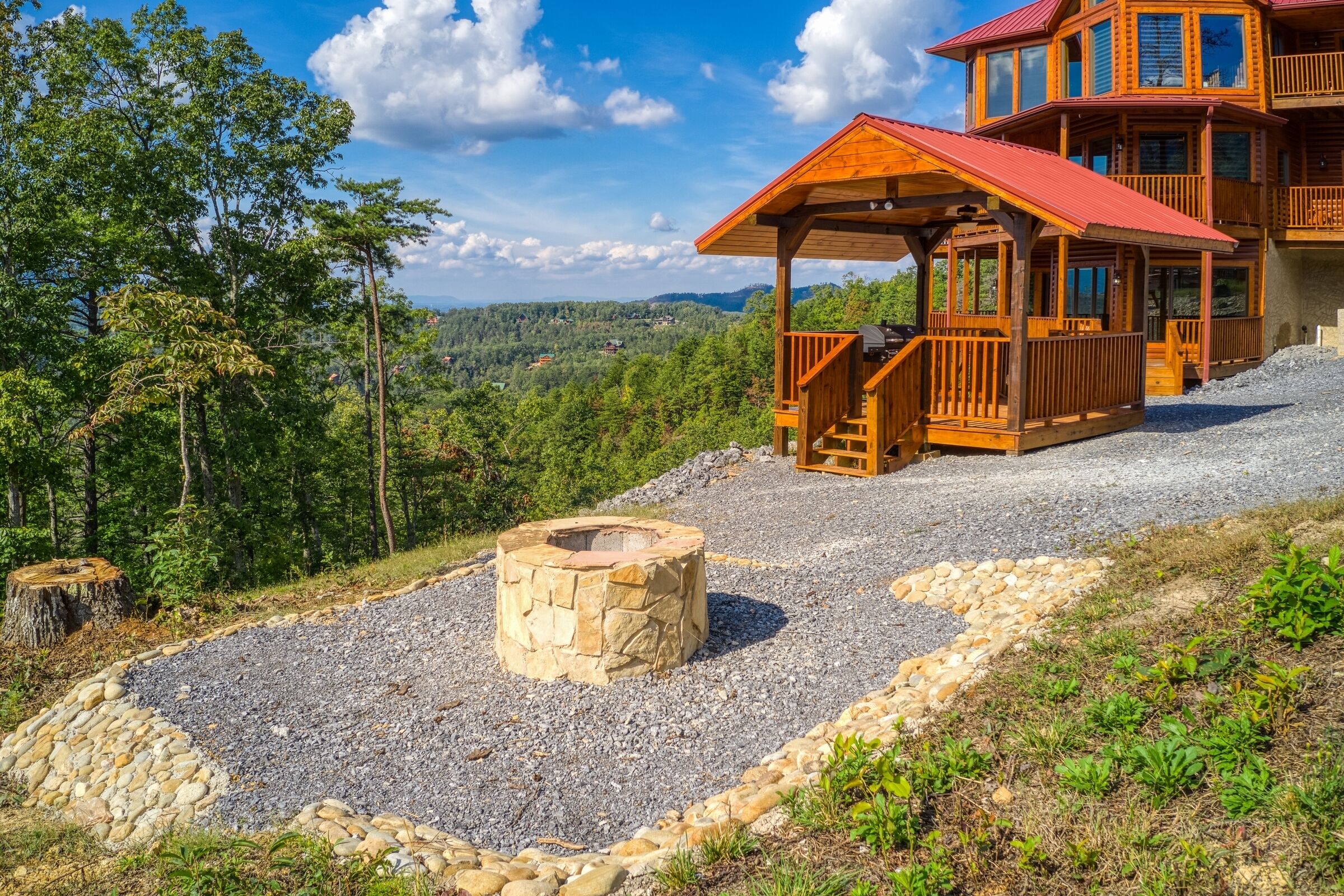 Une cabane dotée d’un foyer en pierre, d’une terrasse en bois et offrant une vue sur la forêt environnante.