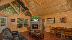 A cozy cabin interior with a fireplace, wooden walls, leather sofas, and a dining area. - Modern Cabin with Fireplace and Game Room (PIGEON FORGE)