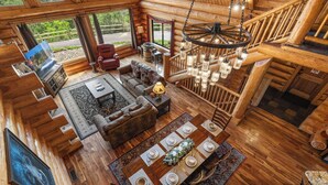 L’intérieur de cette vaste cabane en rondins comprend un coin repas, une cheminée et une grande fenêtre donnant sur un paysage magnifique.