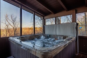 A hot tub with a view of trees and a clear sky through large windows. - Luxury Cabin with Mountain Views and Amenities (GATLINBURG)