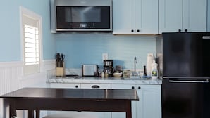 A kitchen with a microwave, coffee maker, and refrigerator.