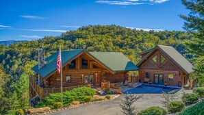 A log cabin with a green roof, a porch, and a flag. - Luxury Log Lodge with Mountain Views (SEVIERVILLE)