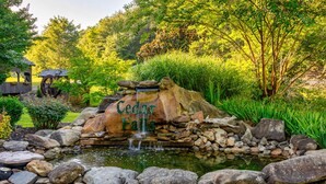 A pond with a waterfall, surrounded by rocks and greenery. - Luxury Log Lodge with Mountain Views (SEVIERVILLE)