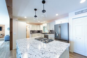 Una cocina moderna con una isla central, electrodomésticos de acero inoxidable e iluminación colgante.
