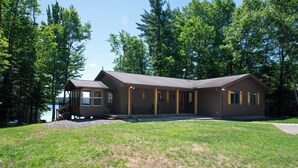 A two-story building with a covered porch, a small deck, and a view of a lake. - Dollar Lake Oasis, Near Downtown and the Chain, Fire Pit, Sandy Beach, W&D, WiFi (Eagle River)
